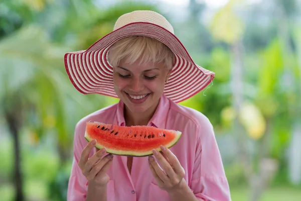 年轻漂亮的女人，戴着帽子，拿着一块西瓜和微笑快乐热带森林背景 — 图库照片