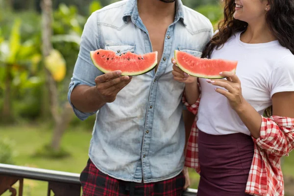 Fechar-se de jovem casal segurando melancia fatia abraçando juntos irreconhecível homem e mulher ao ar livre no terraço de verão — Fotografia de Stock