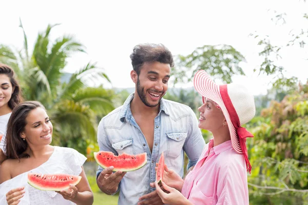 Wesoły Grupa młodych przyjaciół, posiadanie zabawa razem jedzenie arbuza na tarasie w Tropical Forest Mix rasy ludzi komunikacji — Zdjęcie stockowe