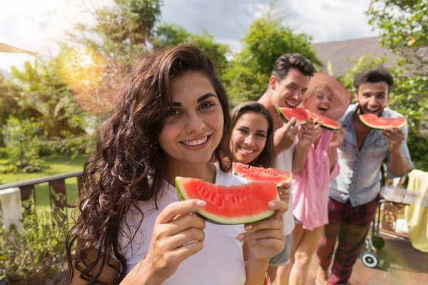 Alegre mujer celebración sandía rebanada sonrisa junto con grupo de amigos comiendo sandía juntos en verano terraza —  Fotos de Stock