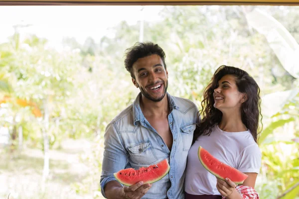 Glückliches Paar hält Wassermelonenscheibe in den Händen fröhliche Mann und Frau umarmen genießen Wassermelone im Freien — Stockfoto