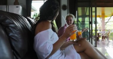 Koç seyretmek Tv oturma odasında oturup insanların içki portakal suyu, genç adam ve kadın grup Modern stüdyo daire iç konuşmaya sabah