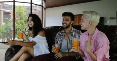 Koç seyretmek Tv oturan insanlar, oturma odasında kız değiştirme kanalları suyu, genç adam ve kadın grup Modern Daire konuşmaya sabah İçilir
