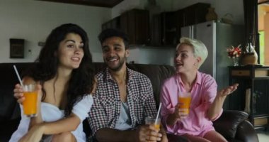 Koç seyretmek Tv oturma odasında oturup insanların içki portakal suyu, genç adam ve kadın grup Modern stüdyo daire iç konuşmaya sabah