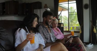 İnsanlar Tablet bilgisayar suyu, genç adam ve kadın grup Modern Daire iç konuşmaya sabah iç oturma odasında Tv izlerken Koç kullanın