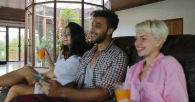 İnsanlar Tablet bilgisayar suyu, genç adam ve kadın grup Modern Daire iç konuşmaya sabah iç oturma odasında Tv izlerken Koç kullanın