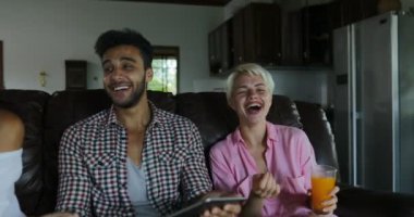 İnsanlar Tablet bilgisayar suyu, genç adam ve kadın grup Modern Daire iç konuşmaya sabah iç oturma odasında Tv izlerken Koç kullanın