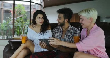 İnsanlar Tablet bilgisayar suyu, genç adam ve kadın grup Modern Daire iç konuşmaya sabah iç oturma odasında Tv izlerken Koç kullanın