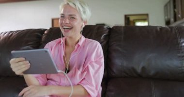 Kadın Tablet bilgisayar kullanarak gülümseyen kız Internet iletişim konuşan Koç oturma odasında oturmak Online Video çağrısı yapma veya paylaşma