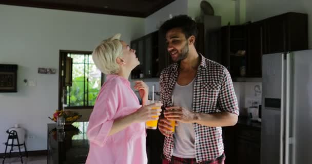 Couple boivent la danse de jus d'orange dans la cuisine, jeune homme heureux et femme communication du matin dans l'appartement moderne — Video