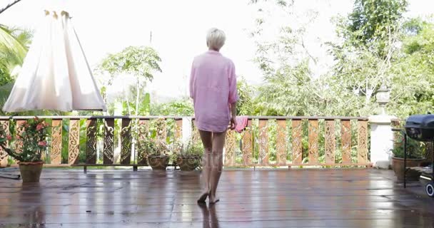 Meisje uitgaan naar terras uitrekken armen terug achteraanzicht, Blonde vrouw ochtend uitzicht van de Tropic Forest — Stockvideo