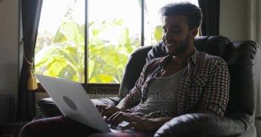 Koltuk kullanan dizüstü bilgisayarda, çalışma vasıl ev, tipik Internet mutlu gülümseyerek sörf adam oturan adam