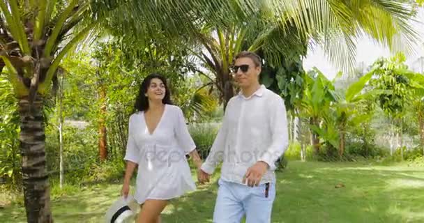 Par som går hand i hand i Tropical Garden talar, lycklig Man och kvinna Utomhus — Stockvideo