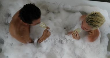 En iyi açılı görünüş, erkek ve kadın sevgilisi konuşurken genç çift banyo birlikte içki şampanya içinde Spa evde keyfini çıkarın