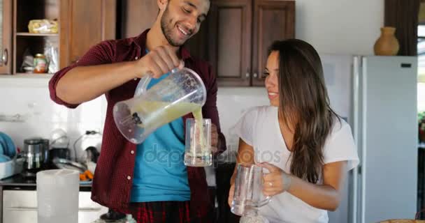 Par häll färsk Juice från Blender i glasögon Man och kvinna i kök talar grupp glada leende — Stockvideo