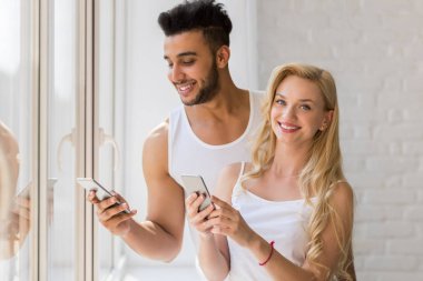 Genç güzel çift Stand yakınındaki hücre akıllı telefon mutlu gülümseme İspanyol adam kadın kullanarak büyük penceresi