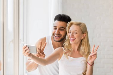 Genç güzel çift pencere, Selfie fotoğrafta akıllı telefonu standı