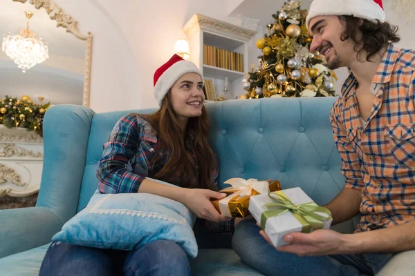 Noel tatil mutlu çift mevcut kutuları veren yeni yıl Santa şapka kap, gülümseyen kadın ve erkek giyim — Stok fotoğraf