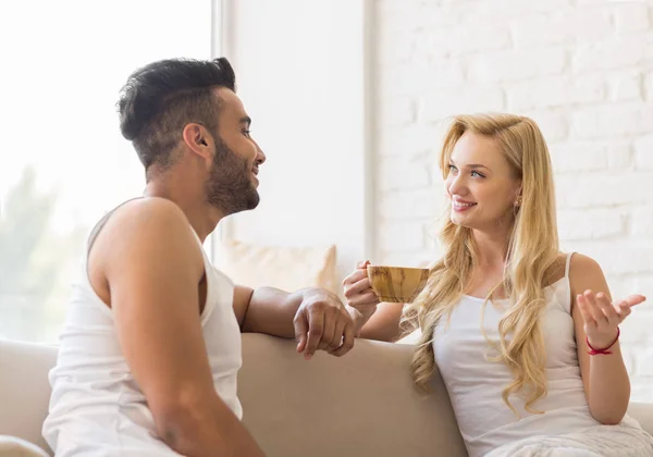 Jonge mooie paar zitten op Sofa praten, Spaanse Man vrouw drinken's ochtends koffie beker — Stockfoto