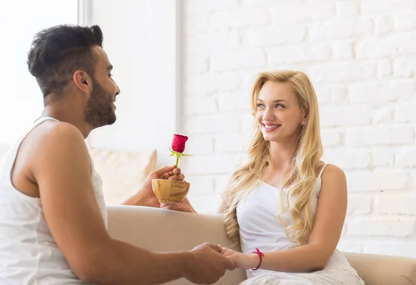 Joven pareja hermosa se sienta en el sofá hablando, mujer hispana bebe taza de café de la mañana — Foto de Stock