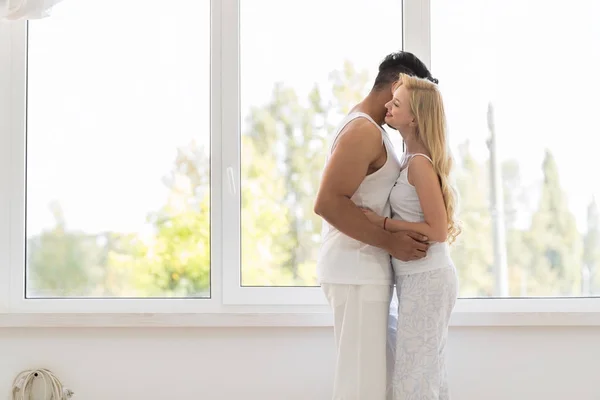 Unga vackra paret stå nära fönster omfamning, lyckligt leende spansktalande Man och kvinna — Stockfoto