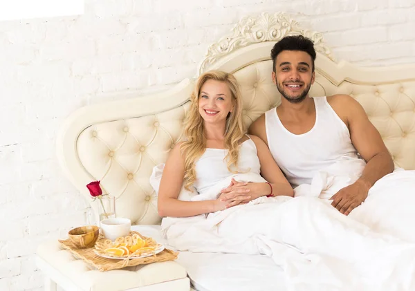 Casal jovem deitado na cama comer manhã com flor de rosa vermelha, sorriso feliz hispânico homem e mulher — Fotografia de Stock