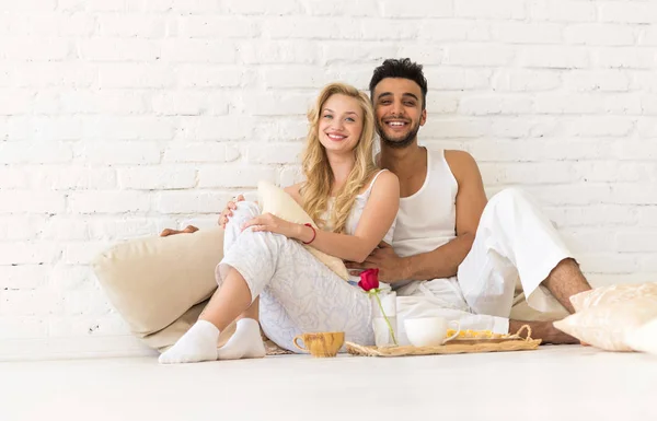 年轻夫妇坐在枕头地板上, 快乐的拉美裔男子和妇女早餐托盘情侣在卧室 — 图库照片