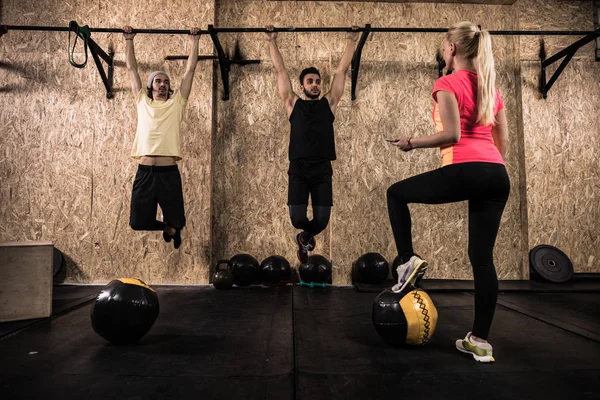 Sport Fitness grupa ludzi robi pociągnij Ups poziomego paska Crossfit szkolenia, trener młodej kobiety zdrowe — Zdjęcie stockowe