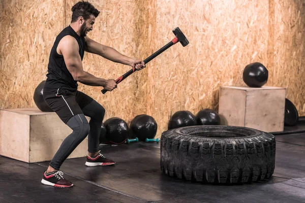 体育健身男子击中车轮轮胎与锤子雪橇 Crossfit 训练, 年轻健康的家伙 — 图库照片