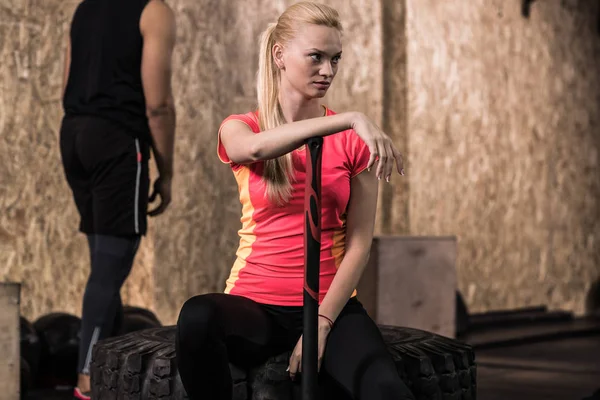 Sport Fitness People Group Equipo de entrenamiento Crossfit, Mujer sana y joven seria se sienta en el neumático —  Fotos de Stock