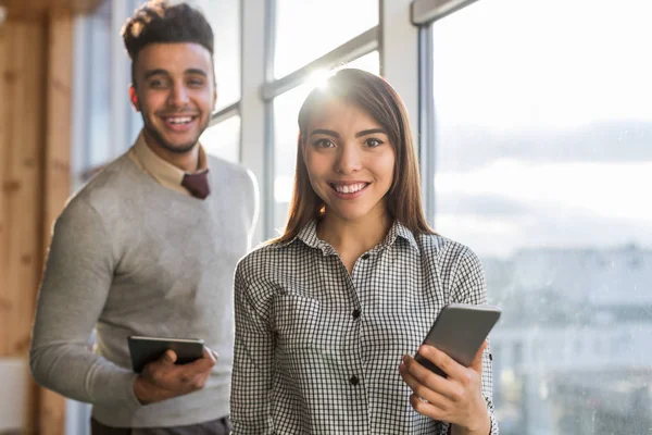 Misture raça homem de negócios mulher usando celular inteligente telefone stand na frente janela panorâmica feliz sorridente empresários no centro de co-working — Fotografia de Stock