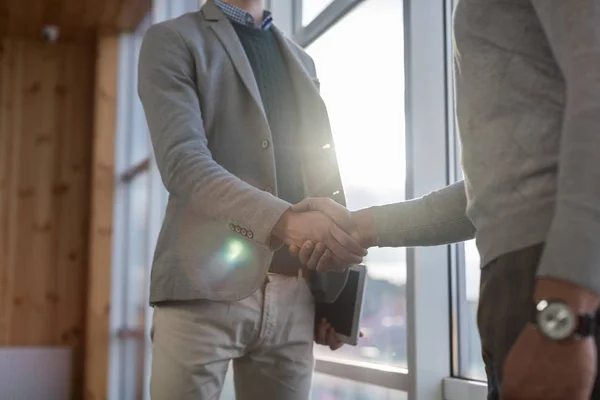 Twee Man Shake Hand overeenkomst naaiatelier zakencentrum Business Team collega's staan op de voorgrond groot panoramisch venster — Stockfoto