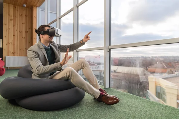 Homme d'affaires Portez des lunettes numériques Tenez-vous à la main Réalité virtuelle Asseyez-vous devant la fenêtre panoramique Homme d'affaires Coworking Center — Photo
