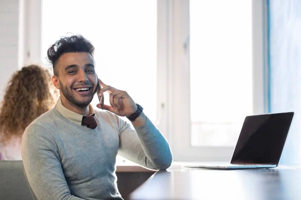 Uomo d'affari ispanico che parla su computer portatile di chiamata del telefono cellulare uomo d'affari nel centro di cooworking — Foto Stock