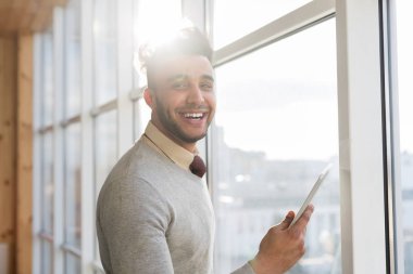 İspanyol iş adam kullanarak hücre akıllı telefon Stand ön panoramik pencere mutlu gülümseyen iş adamı olarak Coworking Merkezi