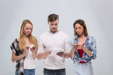 Sıradan insanların grup, genç adam iki kadın mutlu kullanarak hücre akıllı telefon ağ iletişimi gülümseyin