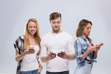 Sıradan insanların grup, genç adam iki kadın mutlu kullanarak hücre akıllı telefon ağ iletişimi gülümseyin
