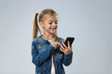 Küçük genç kız kullanarak hücre akıllı telefon, küçük mutlu gülümseyen çocuk evlat