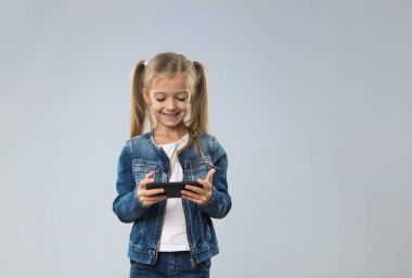 Küçük genç kız kullanarak hücre akıllı telefon, küçük mutlu gülümseyen çocuk evlat