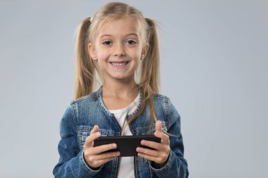 Küçük genç kız kullanarak hücre akıllı telefon, küçük mutlu gülümseyen çocuk evlat