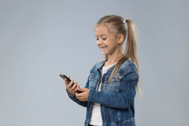 Küçük genç kız kullanarak hücre akıllı telefon, küçük mutlu gülümseyen çocuk evlat
