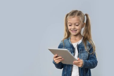 İzole Tablet bilgisayar mutlu gülümseyerek aşınma Kot ceket kullanan güzel küçük kız