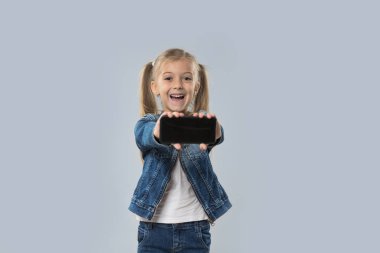 Güzel küçük kız tutun hücre akıllı telefon boş ekran aşınma Kot ceket gülümseyen mutlu izole