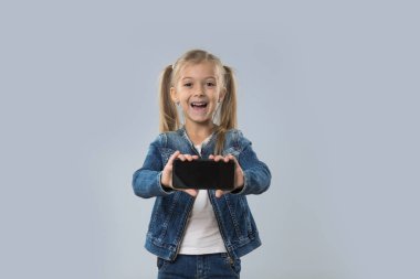 Güzel küçük kız tutun hücre akıllı telefon boş ekran aşınma Kot ceket gülümseyen mutlu izole