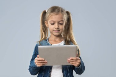 İzole Tablet bilgisayar mutlu gülümseyerek aşınma Kot ceket kullanan güzel küçük kız