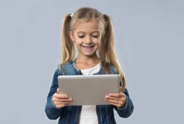 İzole Tablet bilgisayar mutlu gülümseyerek aşınma Kot ceket kullanan güzel küçük kız