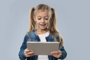 İzole Tablet bilgisayar mutlu gülümseyerek aşınma Kot ceket kullanan güzel küçük kız