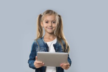 İzole Tablet bilgisayar mutlu gülümseyerek aşınma Kot ceket kullanan güzel küçük kız