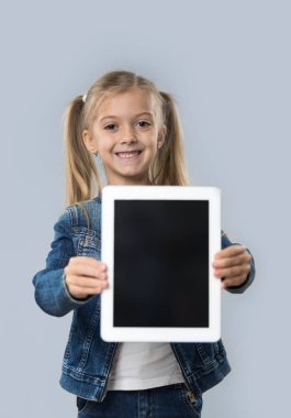 Güzel küçük kız tutun Tablet bilgisayar boşaltmak izole ekran mutlu gülümseyen aşınma Kot ceket