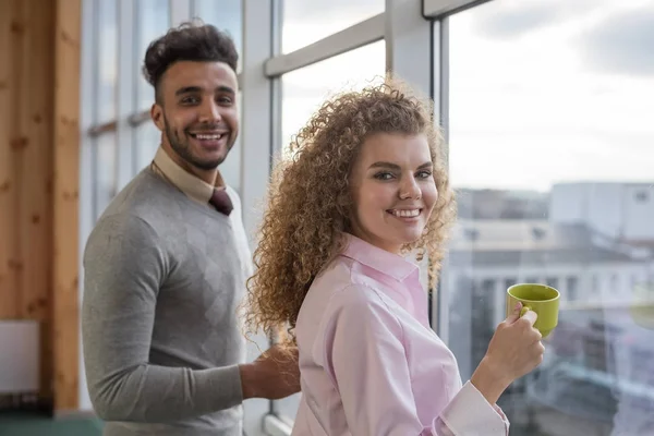 Empresarios Pareja sostienen tazas Pausa para el café en el centro de coworking Colaboradores de pie frente a la ventana panorámica — Foto de Stock